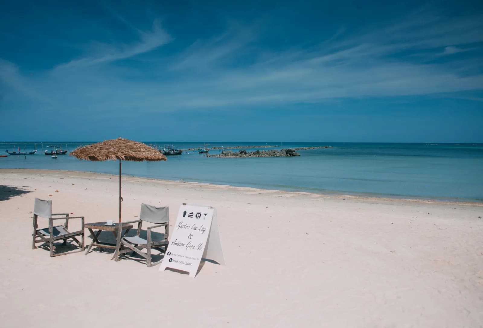 White sand of Sai Kaew Beach with sun loungers and distant boats